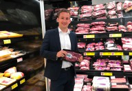 Thomas Reiter, Regionalverkaufsleiter, steht vor der Fleischabteilung und hält eine Packung abgepackte Fleischstücke vor die Kamera.